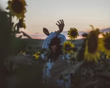 woman-with-arms-raised-amidst-blooming-sunflowers-sunset